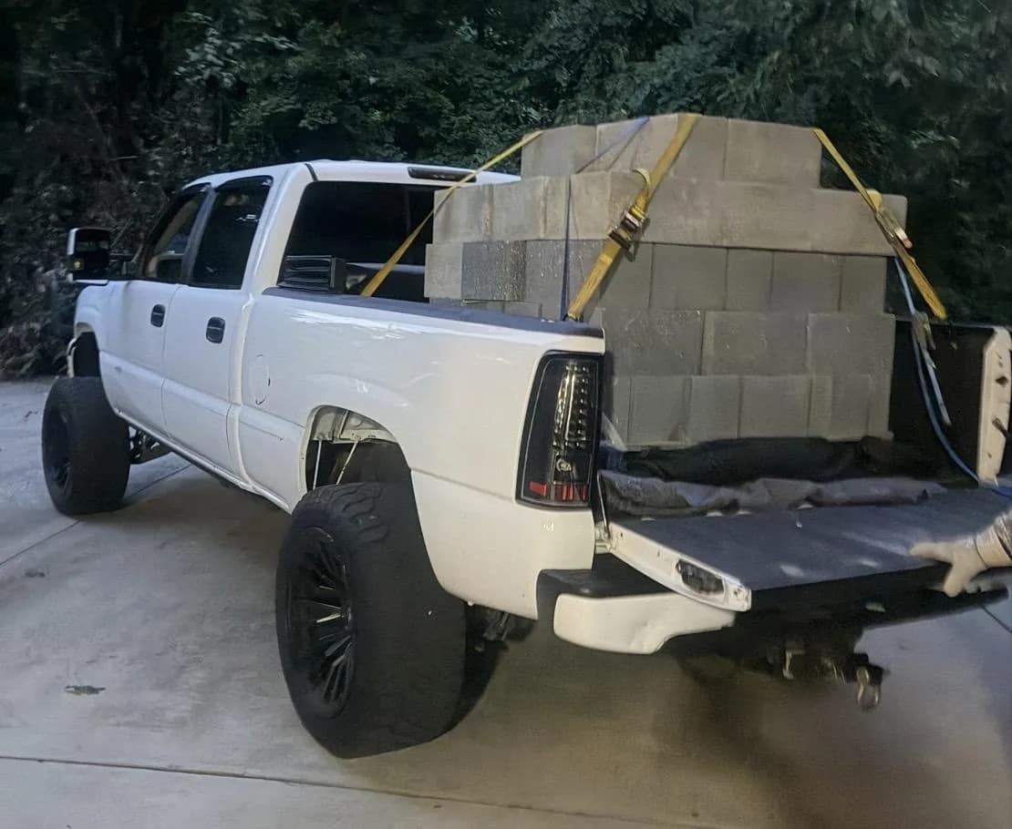 Pickup bed stacked and strapped with 65 heavyweight concrete blocks
