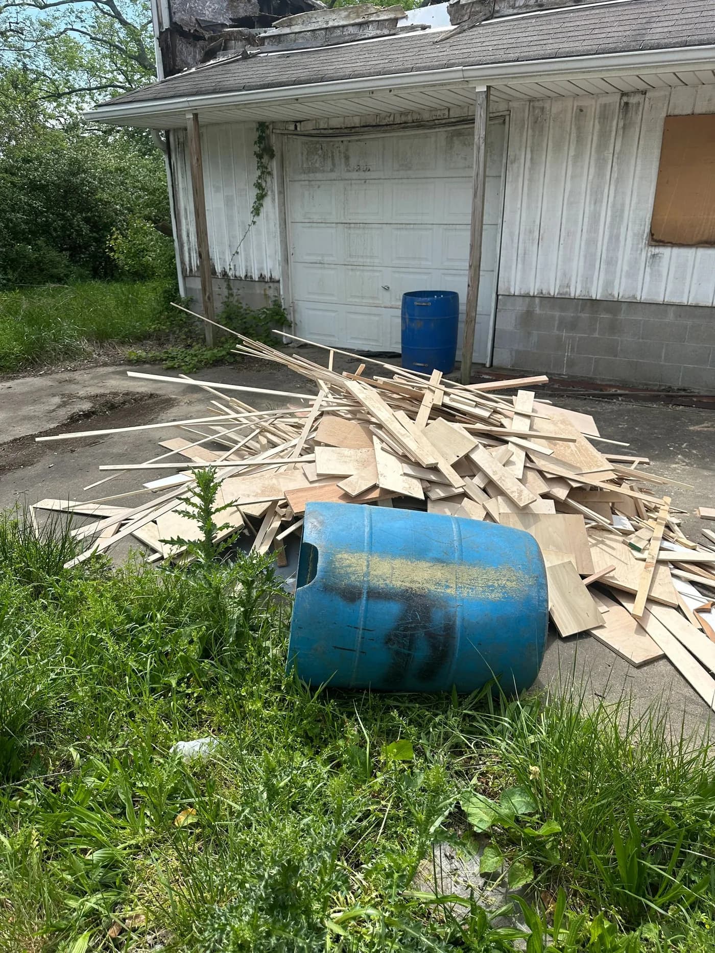 Pile of scrap lumber and debris beside a garage